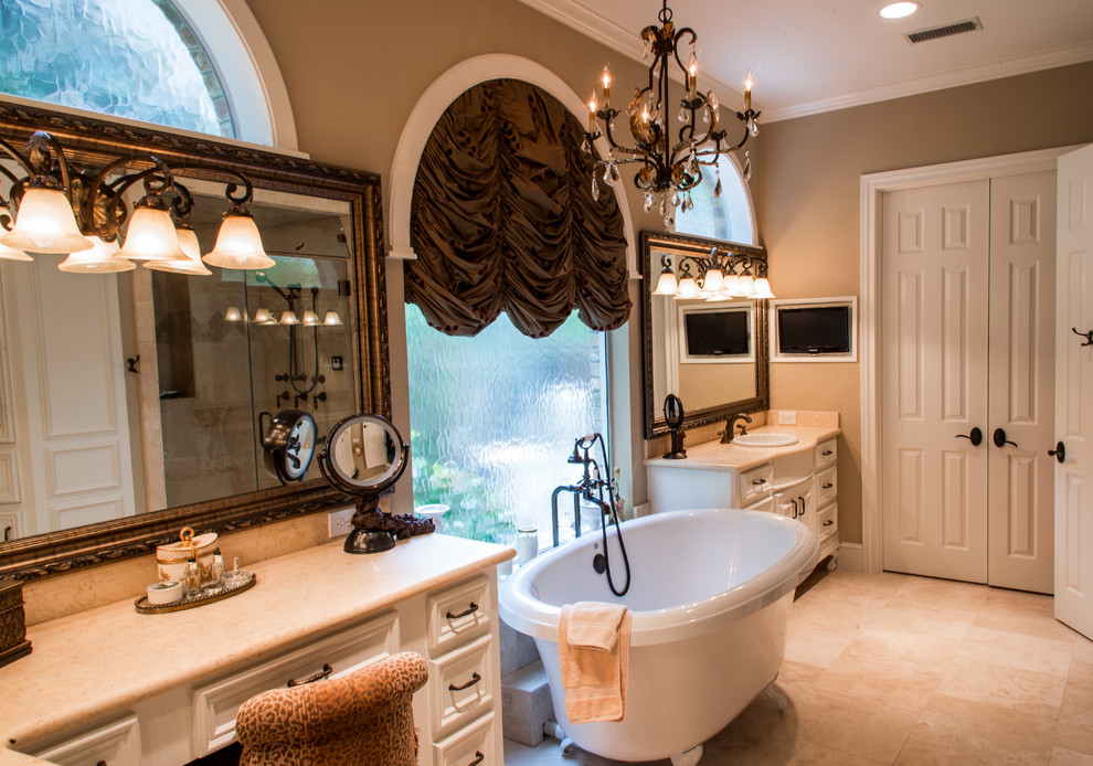 This is an example of a medium sized mediterranean ensuite bathroom in Houston with recessed-panel cabinets, white cabinets, a claw-foot bath, beige tiles, porcelain tiles, beige walls, ceramic flooring, a built-in sink and limestone worktops.
