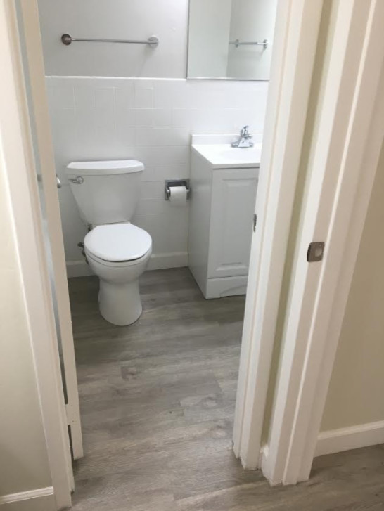 Kleines Klassisches Duschbad mit profilierten Schrankfronten, weißen Schränken, Toilette mit Aufsatzspülkasten, weißer Wandfarbe, braunem Holzboden, Quarzwerkstein-Waschtisch, braunem Boden und weißer Waschtischplatte in San Francisco