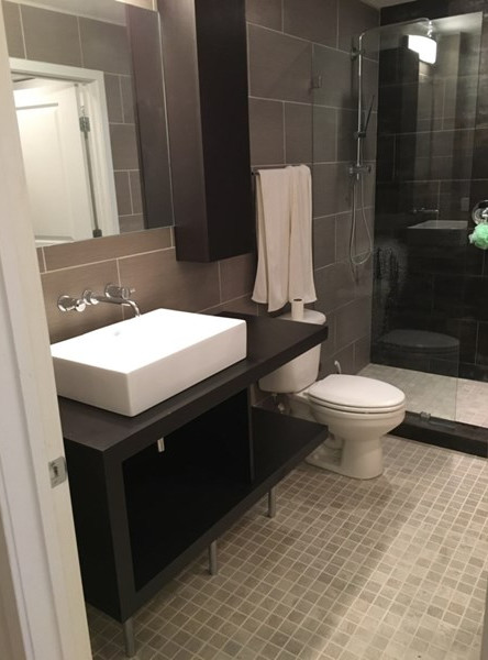 Modern inredning av ett mellanstort badrum med dusch, med möbel-liknande, skåp i mörkt trä, en dusch i en alkov, en toalettstol med separat cisternkåpa, brun kakel, porslinskakel, bruna väggar, mosaikgolv, ett fristående handfat och beiget golv