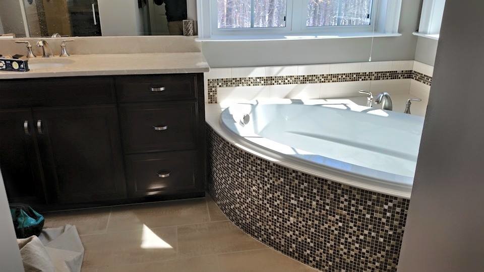 Пример оригинального дизайна: главная ванная комната среднего размера в стиле фьюжн с фасадами с утопленной филенкой, черными фасадами, угловой ванной, унитазом-моноблоком, бежевой плиткой, черной плиткой, разноцветной плиткой, плиткой мозаикой, серыми стенами, полом из известняка, врезной раковиной, столешницей из известняка и бежевым полом