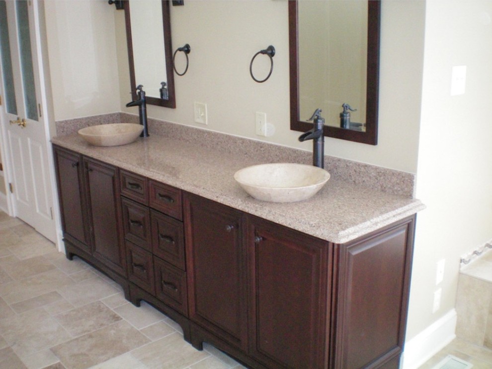 Klassisk inredning av ett mellanstort en-suite badrum, med luckor med upphöjd panel, skåp i mellenmörkt trä, beige kakel, stenhäll, beige väggar, klinkergolv i keramik, ett fristående handfat, granitbänkskiva och beiget golv