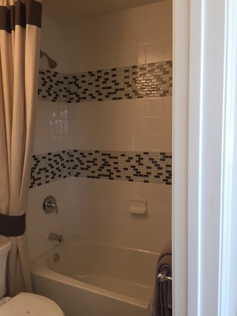 Bild på ett litet vintage badrum med dusch, med svarta skåp, ett badkar i en alkov, en dusch i en alkov, en toalettstol med separat cisternkåpa, svart och vit kakel, grå kakel, vit kakel, keramikplattor, vita väggar, klinkergolv i keramik och bänkskiva i akrylsten