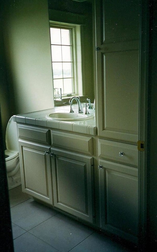 Exempel på ett stort amerikanskt badrum, med ett konsol handfat, luckor med upphöjd panel, beige skåp, kaklad bänkskiva, en dusch i en alkov, en toalettstol med hel cisternkåpa, vit kakel, keramikplattor, vita väggar och klinkergolv i keramik