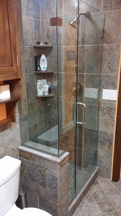 This is an example of a medium sized traditional shower room bathroom in New York with an alcove shower, a two-piece toilet, brown tiles, grey tiles, ceramic tiles, grey walls and ceramic flooring.