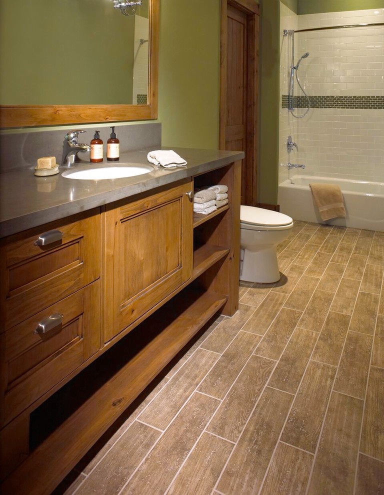 Idée de décoration pour une salle de bain craftsman en bois brun de taille moyenne avec un placard avec porte à panneau encastré, une baignoire en alcôve, un combiné douche/baignoire, un carrelage blanc, un carrelage métro, un mur vert, un sol en bois brun, un lavabo encastré et un sol marron.