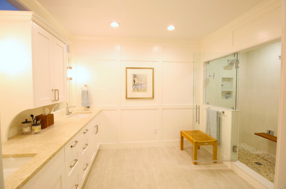 На фото: большая главная ванная комната в стиле неоклассика (современная классика) с фасадами в стиле шейкер, белыми фасадами, душем в нише, белыми стенами, полом из керамогранита, врезной раковиной, столешницей из известняка, бежевым полом, душем с распашными дверями, раздельным унитазом, бежевой плиткой и керамогранитной плиткой