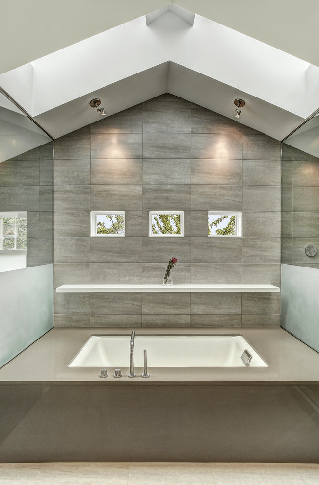 Ispirazione per una stanza da bagno contemporanea con vasca sottopiano, piastrelle grigie, top in quarzo composito, piastrelle in gres porcellanato e pavimento in gres porcellanato