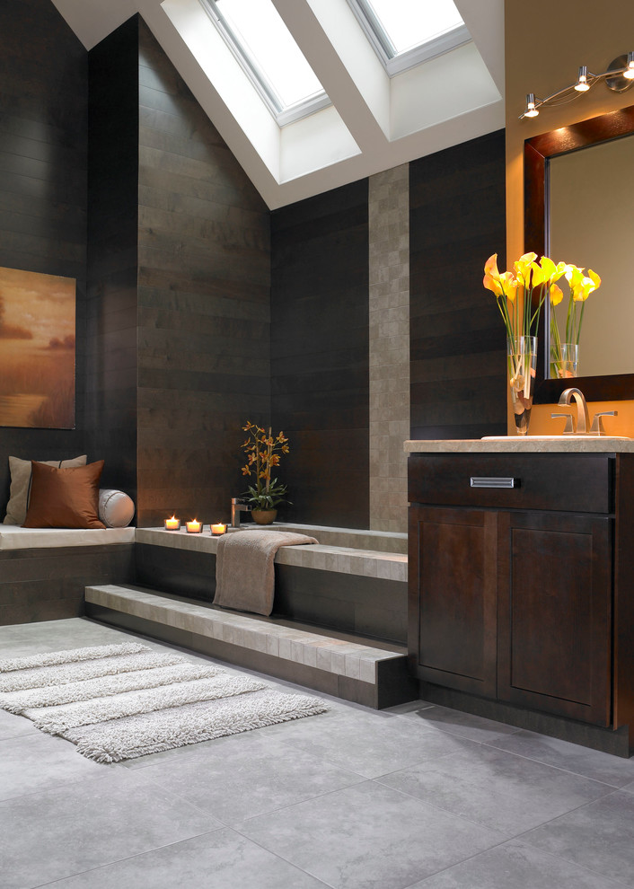 Inspiration for a large contemporary ensuite bathroom in Boise with flat-panel cabinets, dark wood cabinets, a submerged bath, black walls, concrete flooring and a built-in sink.