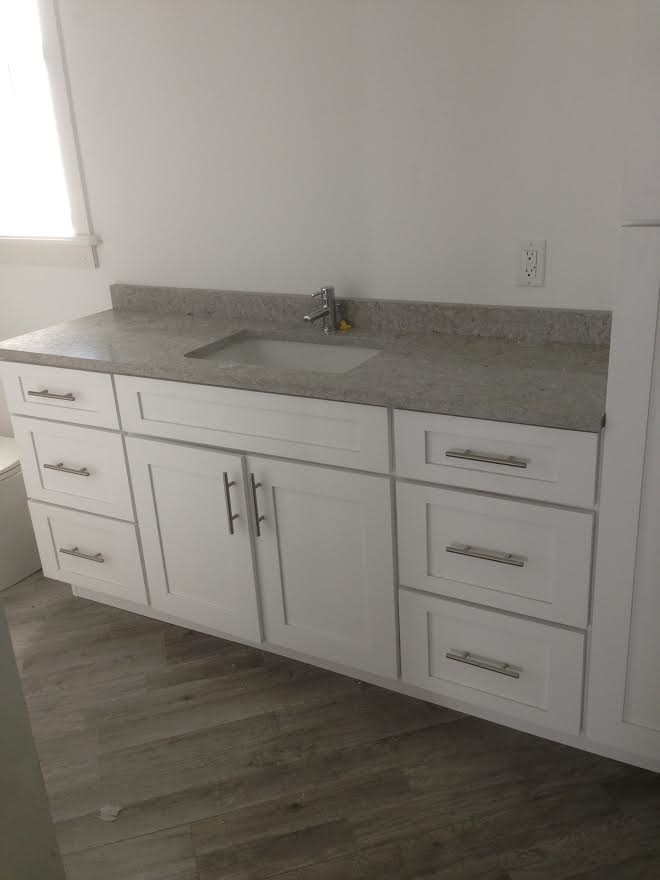 Inredning av ett klassiskt mellanstort grå grått badrum, med vita väggar, mellanmörkt trägolv, brunt golv, skåp i shakerstil, vita skåp, en dusch i en alkov och ett undermonterad handfat