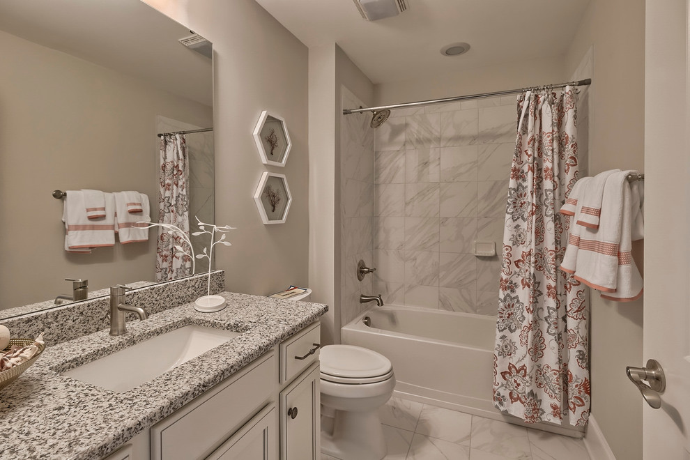Bild på ett mellanstort vintage en-suite badrum, med vita skåp, vit kakel, marmorkakel, beige väggar, marmorgolv, ett undermonterad handfat, granitbänkskiva, luckor med infälld panel, ett badkar i en alkov och en dusch/badkar-kombination