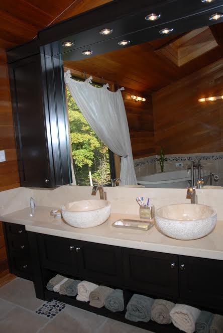 Photo of a large contemporary ensuite bathroom in Toronto with flat-panel cabinets, dark wood cabinets, a freestanding bath, an alcove shower, a one-piece toilet, beige tiles, stone tiles, beige walls, limestone flooring, a vessel sink and marble worktops.
