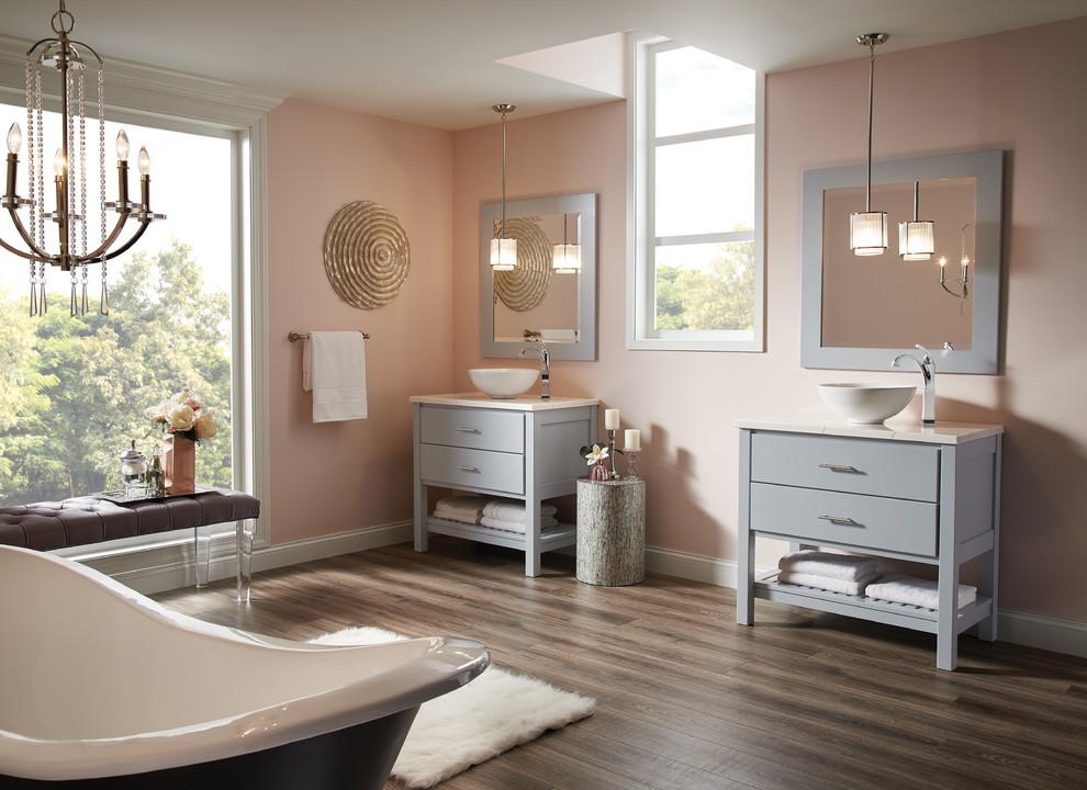 Exemple d'une grande salle de bain principale tendance avec un placard en trompe-l'oeil, des portes de placard grises, une baignoire sur pieds, un mur rose, parquet foncé, une vasque et un plan de toilette en surface solide.