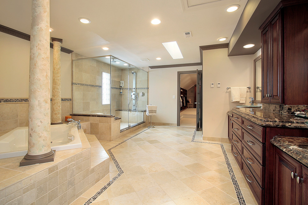 На фото: большая главная ванная комната в классическом стиле с угловым душем, фасадами с выступающей филенкой, темными деревянными фасадами, угловой ванной, бежевыми стенами, полом из известняка, настольной раковиной и столешницей из гранита