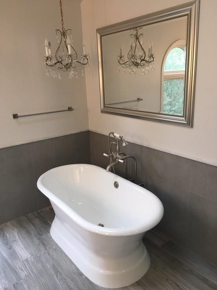 Modelo de cuarto de baño contemporáneo con bañera exenta, baldosas y/o azulejos grises, baldosas y/o azulejos de cerámica, paredes blancas, suelo laminado y suelo gris