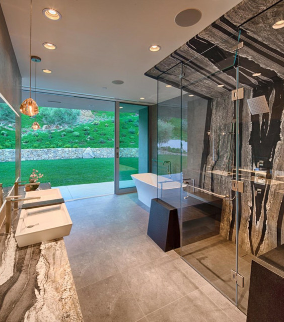 Modern inredning av ett stort en-suite badrum, med ett fristående badkar, en kantlös dusch, en toalettstol med separat cisternkåpa, svart och vit kakel, stenhäll, grå väggar, travertin golv, ett fristående handfat, marmorbänkskiva, grått golv och dusch med gångjärnsdörr