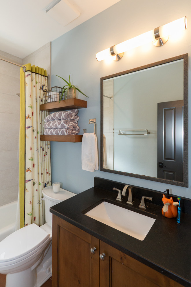 Cette image montre une petite salle de bain sud-ouest américain en bois brun pour enfant avec un placard avec porte à panneau encastré, une baignoire encastrée, un combiné douche/baignoire, WC séparés, un carrelage noir et blanc, des carreaux de porcelaine, un mur bleu, un sol en brique, un lavabo encastré, un plan de toilette en quartz modifié, un sol rouge, une cabine de douche avec un rideau et un plan de toilette noir.