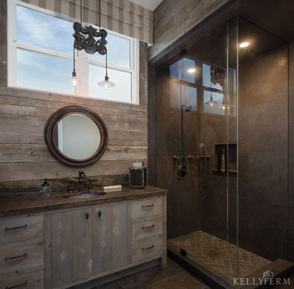 Immagine di una stanza da bagno costiera con lavabo sottopiano, consolle stile comò, ante con finitura invecchiata e piastrelle nere