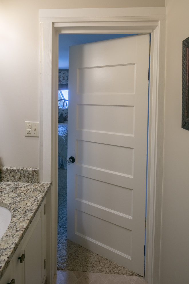 Cette photo montre une salle de bain montagne de taille moyenne avec un placard avec porte à panneau surélevé, des portes de placard blanches, un mur beige et un sol beige.