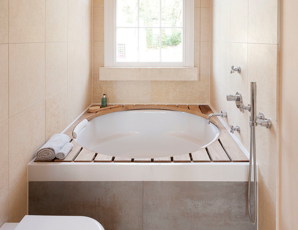 Cette photo montre une petite salle de bain tendance pour enfant avec une baignoire en alcôve, un combiné douche/baignoire, WC suspendus, un mur beige et un sol en calcaire.