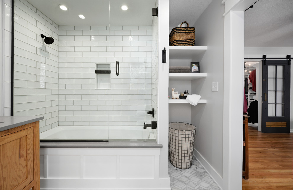 Photo of a small traditional ensuite bathroom in Kansas City with recessed-panel cabinets, medium wood cabinets, an alcove bath, a shower/bath combination, white tiles, ceramic tiles, white walls, ceramic flooring, grey floors, a sliding door and grey worktops.