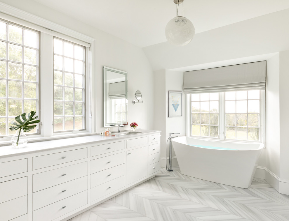 Transitional master white floor freestanding bathtub photo in New York with flat-panel cabinets, white cabinets, white walls, an undermount sink and white countertops