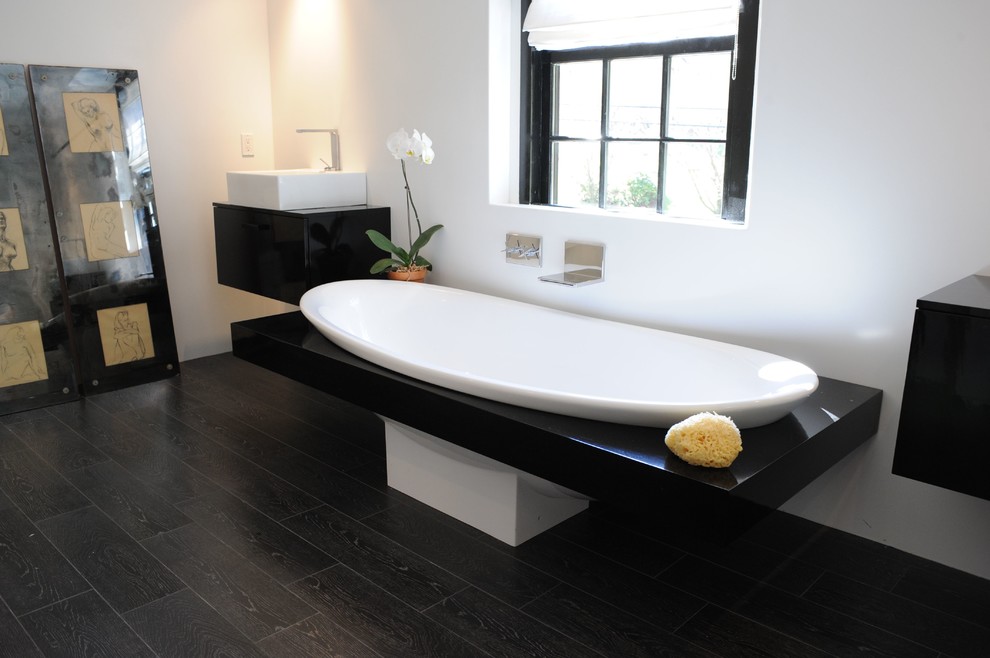 This is an example of a contemporary ensuite bathroom in New York with a built-in bath, white walls, dark hardwood flooring, a vessel sink and brown floors.