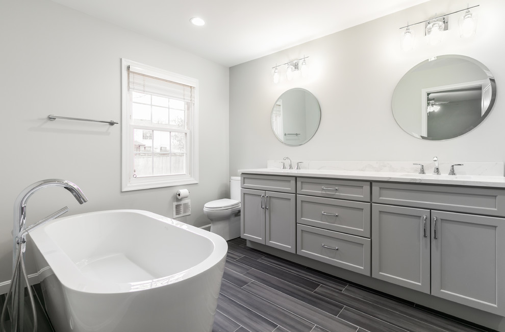 Bathroom - large contemporary master porcelain tile and gray floor bathroom idea in DC Metro with recessed-panel cabinets, gray cabinets, a two-piece toilet, gray walls, an undermount sink, a hinged shower door and white countertops