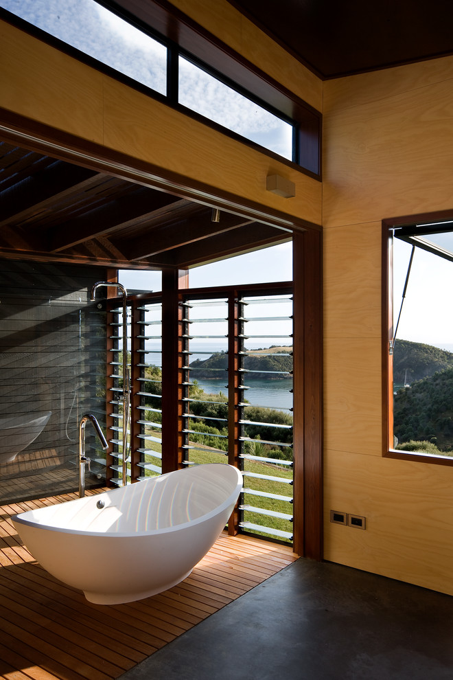 Diseño de cuarto de baño principal contemporáneo con bañera exenta, ducha abierta, suelo de madera oscura y paredes amarillas