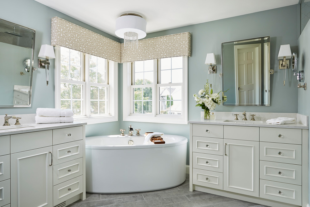 Klassisk inredning av ett mellanstort en-suite badrum, med luckor med infälld panel, vita skåp, ett fristående badkar, blå väggar, klinkergolv i keramik, ett undermonterad handfat, granitbänkskiva och grått golv