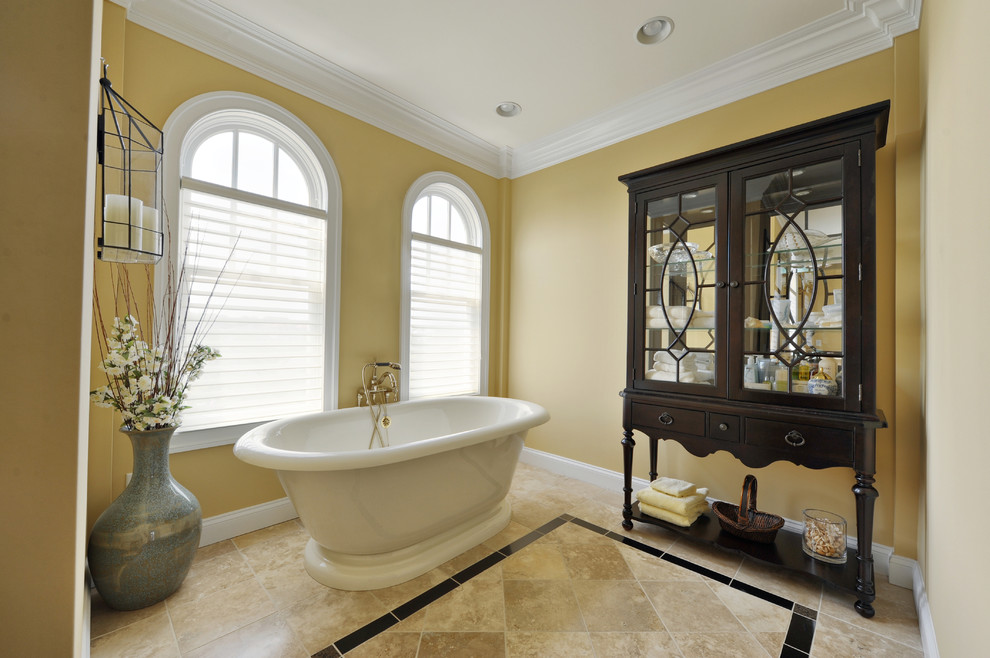 Esempio di una stanza da bagno classica con vasca freestanding e pareti gialle