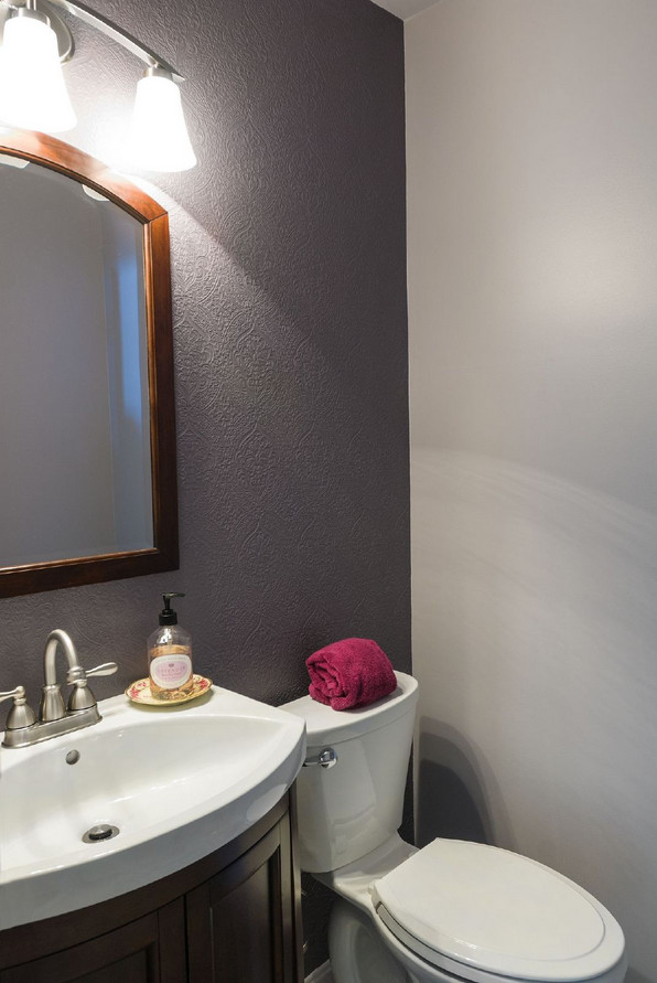 Klassisk inredning av ett litet badrum med dusch, med luckor med infälld panel, skåp i mörkt trä, en toalettstol med separat cisternkåpa, lila väggar, ett piedestal handfat och bänkskiva i akrylsten