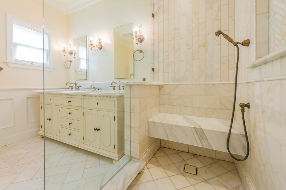 Example of a mid-sized classic master beige tile and marble tile marble floor and beige floor alcove shower design in Los Angeles with recessed-panel cabinets, distressed cabinets, beige walls, an undermount sink, marble countertops and a hinged shower door