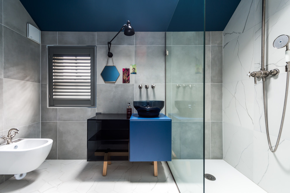 This is an example of a medium sized contemporary shower room bathroom in London with freestanding cabinets, blue cabinets, a walk-in shower, a one-piece toilet, grey tiles, stone slabs, grey walls, porcelain flooring, a vessel sink and laminate worktops.