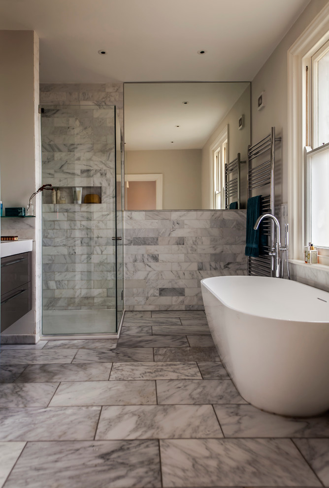 Idéer för små funkis en-suite badrum, med släta luckor, ett fristående badkar, en toalettstol med hel cisternkåpa, grå kakel, stenkakel, grå väggar, marmorgolv, en hörndusch och skåp i mörkt trä