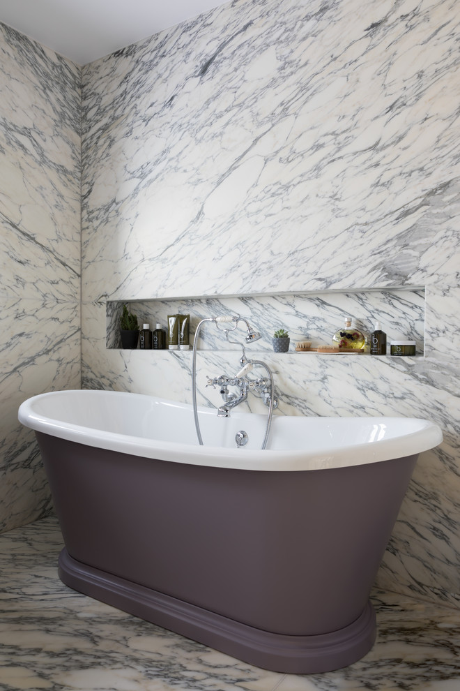 Medium sized contemporary grey and purple bathroom in London with a freestanding bath, marble tiles, marble flooring, white floors and a wall niche.