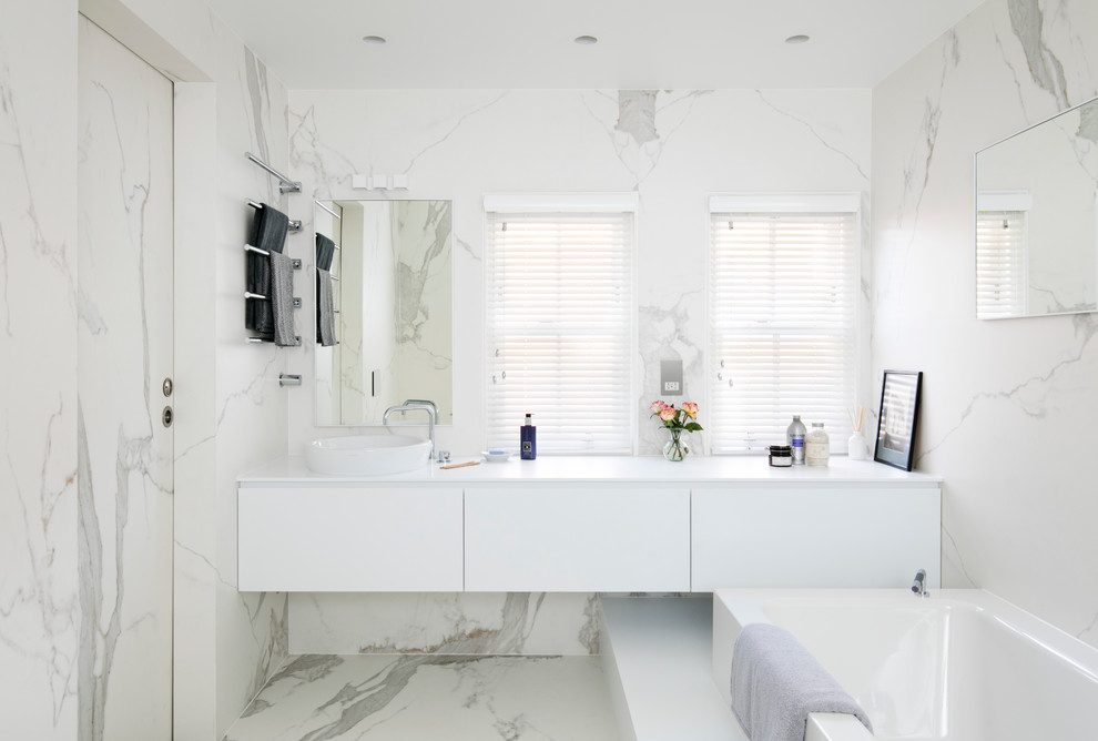 На фото: главная ванная комната в современном стиле с плоскими фасадами, белыми фасадами, белой плиткой, плиткой из листового камня и настольной раковиной с
