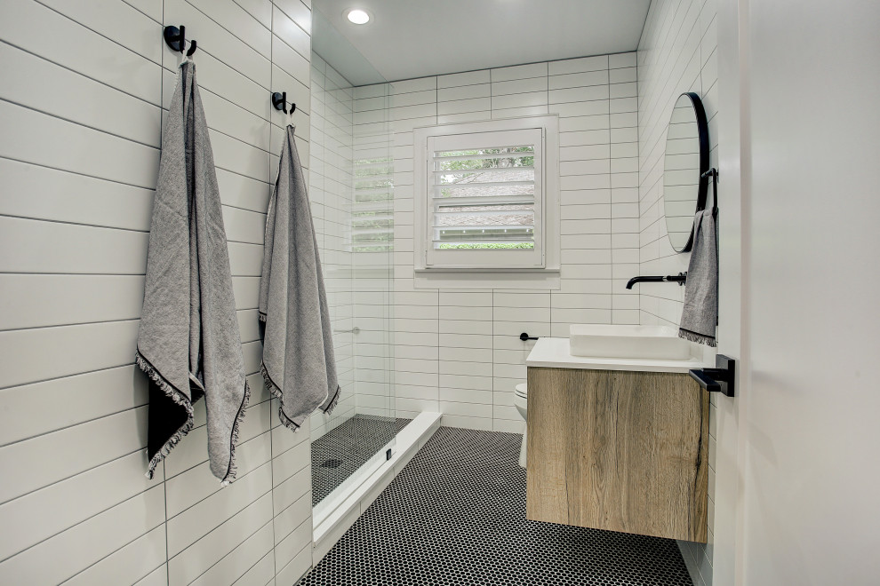 Стильный дизайн: большая главная ванная комната в стиле модернизм с плоскими фасадами, светлыми деревянными фасадами, отдельно стоящей ванной, унитазом-моноблоком, настольной раковиной, белой столешницей, душем в нише, белой плиткой, удлиненной плиткой, белыми стенами, разноцветным полом и душем с раздвижными дверями - последний тренд