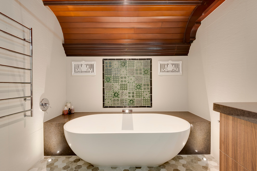 На фото: ванная комната в современном стиле с врезной раковиной, столешницей из искусственного кварца, отдельно стоящей ванной и керамогранитной плиткой