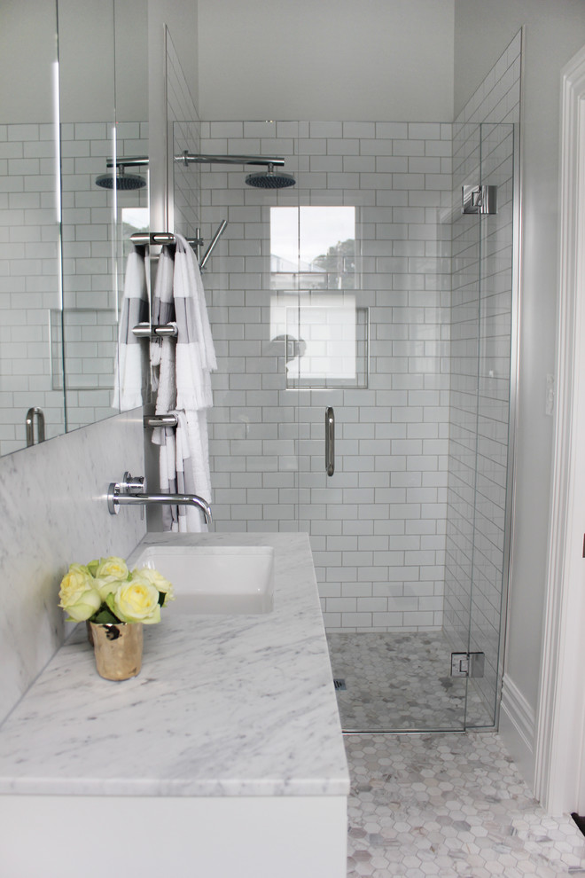 Klassisk inredning av ett litet en-suite badrum, med vita skåp, ett fristående badkar, en dusch i en alkov, vit kakel, tunnelbanekakel, vita väggar, mosaikgolv, marmorbänkskiva och ett undermonterad handfat
