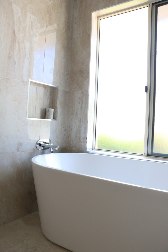 На фото: большая главная ванная комната в современном стиле с отдельно стоящей ванной, угловым душем, бежевой плиткой, керамогранитной плиткой, бежевыми стенами, полом из керамогранита, настольной раковиной, столешницей из искусственного камня, бежевым полом, душем с распашными дверями и белой столешницей