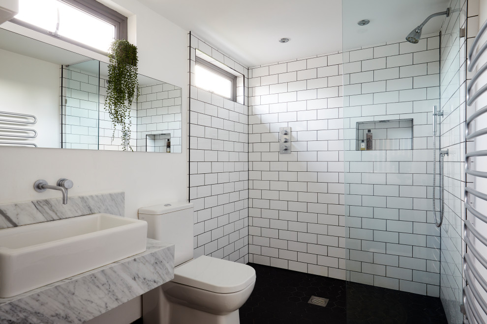 This is an example of a contemporary bathroom in London with a built-in shower, a two-piece toilet, white tiles, metro tiles, white walls, black floors, an open shower and grey worktops.