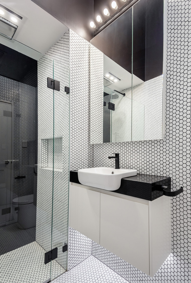 Bild på ett funkis svart svart badrum, med släta luckor, vita skåp, en kantlös dusch, vit kakel, mosaik, mosaikgolv, ett nedsänkt handfat, vitt golv och dusch med gångjärnsdörr