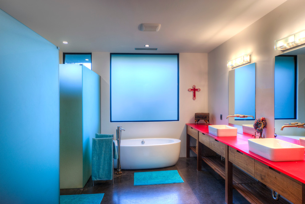 Стильный дизайн: главная ванная комната среднего размера: освещение в современном стиле с настольной раковиной, фасадами цвета дерева среднего тона, отдельно стоящей ванной, угловым душем, раздельным унитазом, белыми стенами, бетонным полом и плоскими фасадами - последний тренд