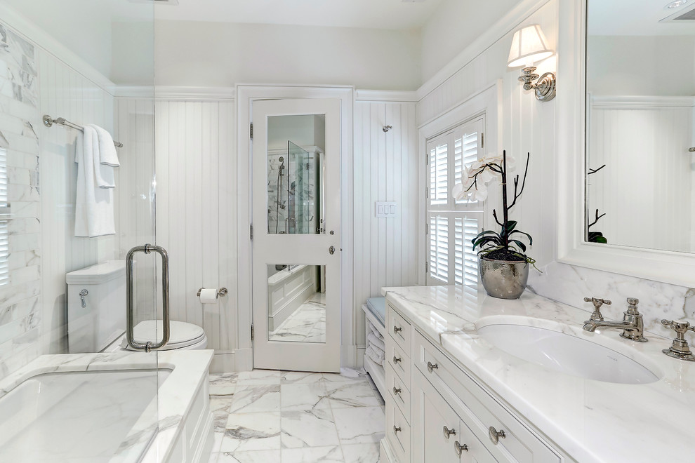 Свежая идея для дизайна: главная ванная комната среднего размера в классическом стиле с фасадами с утопленной филенкой, белыми фасадами, полновстраиваемой ванной, душем над ванной, раздельным унитазом, белой плиткой, белыми стенами, мраморным полом, врезной раковиной, мраморной плиткой и открытым душем - отличное фото интерьера