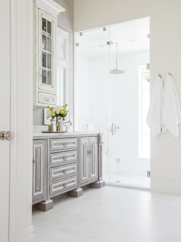 Inspiration for a mid-sized timeless master porcelain tile and white floor bathroom remodel in Jacksonville with beaded inset cabinets, distressed cabinets, gray walls, an undermount sink, solid surface countertops and a hinged shower door