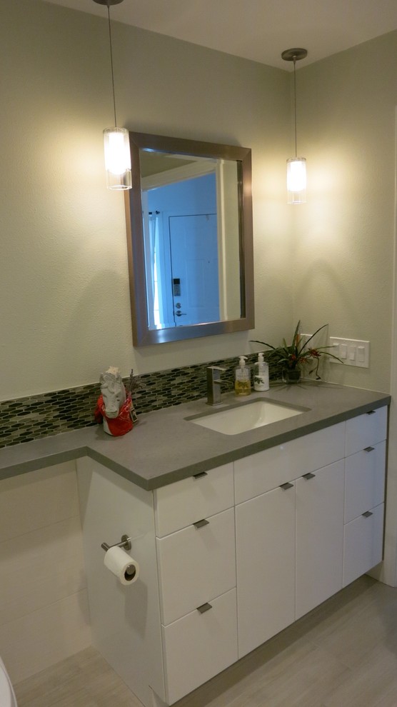 Example of a mid-sized minimalist beige tile and porcelain tile porcelain tile bathroom design in San Francisco with flat-panel cabinets, white cabinets, a one-piece toilet, white walls and an undermount sink