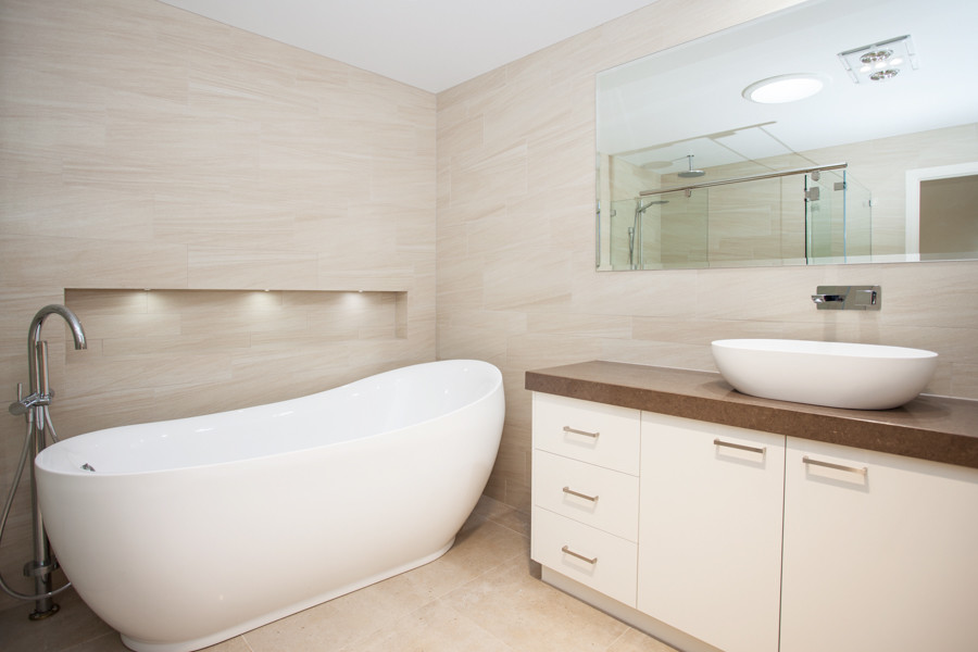 Inspiration for a medium sized contemporary family bathroom in Brisbane with a vessel sink, flat-panel cabinets, white cabinets, solid surface worktops, a freestanding bath, a double shower, beige tiles, porcelain tiles, white walls and porcelain flooring.
