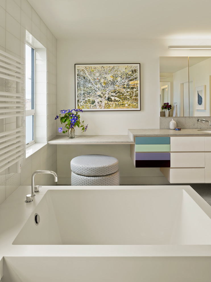 Inspiration för moderna grått badrum, med ett undermonterad handfat, släta luckor, vita skåp, ett fristående badkar och vita väggar