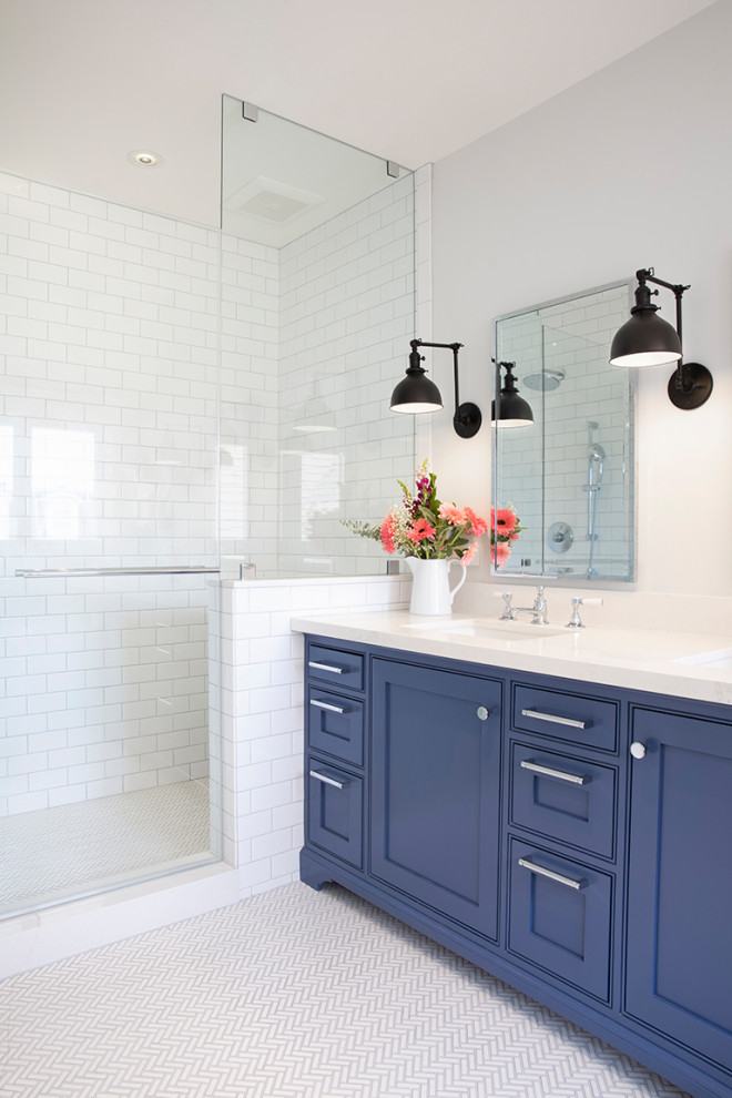 Стильный дизайн: ванная комната среднего размера в стиле неоклассика (современная классика) с фасадами в стиле шейкер, синими фасадами, отдельно стоящей ванной, душем в нише, унитазом-моноблоком, белой плиткой, керамической плиткой, белыми стенами, полом из мозаичной плитки, врезной раковиной, столешницей из искусственного кварца, белым полом, душем с распашными дверями, белой столешницей, нишей, тумбой под две раковины, встроенной тумбой и душевой кабиной - последний тренд