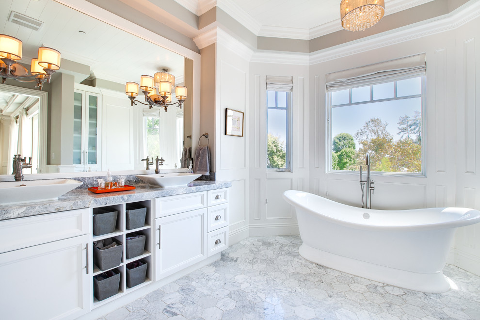 Photo of a nautical bathroom in Los Angeles with recessed-panel cabinets, white cabinets, a freestanding bath, white walls, a vessel sink, grey floors, grey worktops, double sinks, a built in vanity unit and panelled walls.